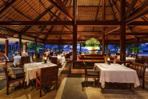 丹戎The Oberoi Beach Resort, Lombok的餐厅设有白色的桌椅和大型天花板。