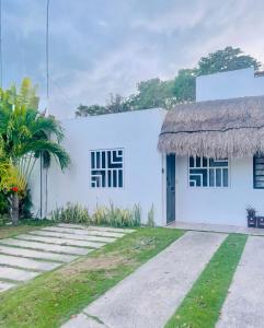 莫雷洛斯港Casa Puerto Morelos Riviera Maya的白色的建筑,设有两扇窗户和草屋顶