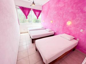 萨尤利塔ITH Amazing Hostel Sayulita的一间设有两张床和粉红色墙壁的客房