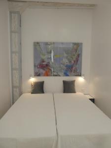 阿维拉San Jose y Maderuelo的卧室配有白色床,上面有绘画作品