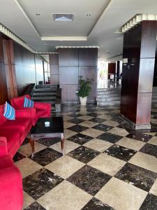阿莱曼Executive Royal Tower Apartments - Sky Lounge的大堂设有红色的沙发和 ⁇ 格地板