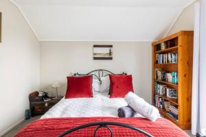 怀卡奈Quiet and cosy的一间卧室配有一张带红色枕头的床和书架