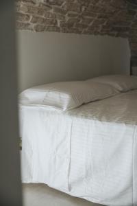 泰尔利齐Santi Medici Apartment的一张带白色床单和砖墙的未铺砌床