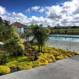 凯里凯里Te Whare Ma的花园设有游泳池,种植了棕榈树和鲜花