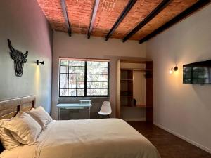 墨西哥城Casa Raffaello的一间卧室配有一张床、一张书桌和一个窗户。