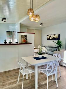 普纳奥亚Tiaki Guesthouse - Cozy Modern Studio - 5min drive from the beach and Punaauia center的厨房以及带白色桌椅的用餐室。