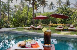琅勃拉邦帕拉索尔布兰科酒店的坐在游泳池旁的桌子上喝一杯
