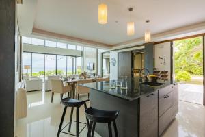 华欣BeachFront Modern 4 Bedroom Pool Villa RV的开放式厨房以及带柜台和凳子的用餐室。
