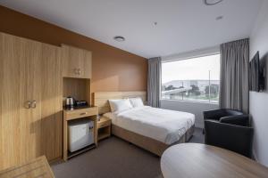奥克兰Manha Hotel Auckland Airport的配有一张床、一张桌子和一张桌子的酒店客房