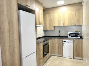 埃斯特里-德阿内乌Apartament comfortable amb vistes i cèntric by RURAL D'ÀNEU的厨房配有木制橱柜和白色冰箱。