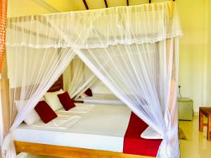锡吉里亚Green Hut Hotel & Restaurant的卧室配有带红色和白色枕头的天蓬床