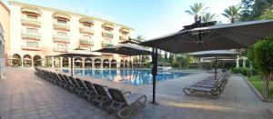 马拉喀什幻影豪华酒店的一座带椅子和遮阳伞的游泳池位于一座建筑旁边