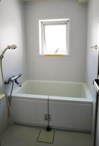 东京Hostel Belle Via Tokyo的带窗户的浴室内的白色浴缸