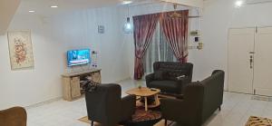 峇株巴辖Aaira Sophea Islamic Homestay的客厅配有两把椅子、一张桌子和电视