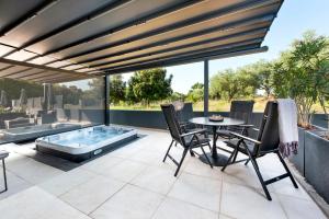 罗维尼Luxury Residence Levante的一个带桌椅和热水浴池的庭院