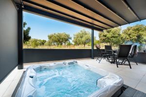罗维尼Luxury Residence Levante的庭院内的热水浴池,配有桌椅