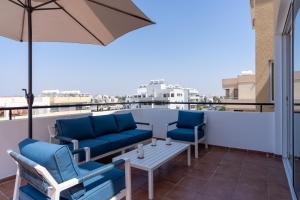 拉纳卡Chloris 3- Bedroom Apartment W/Pool in Larnaca的阳台配有桌椅和雨伞。
