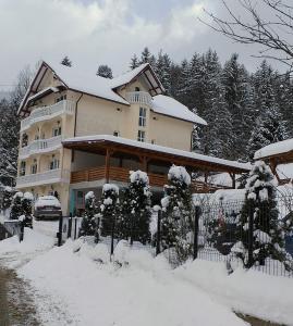 Statjunea BorsaPensiunea Casa Bradet的雪覆盖的房屋,有栅栏