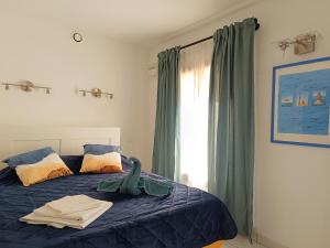 波克罗勒岛Le Clos des Galéjades的一间卧室配有一张带蓝色床单的床和一扇窗户。
