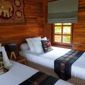 湄南海滩Samui Blue Bird的木墙客房的两张床