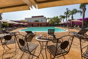 锡拉库扎信天翁酒店的度假村前方带桌椅的游泳池