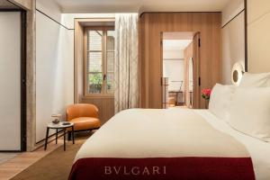 罗马Bulgari Hotel Roma的配有一张床和一把椅子的酒店客房