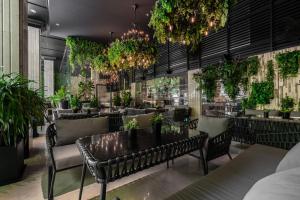 胡志明市百利宫西贡酒店的一间设有桌椅和盆栽的餐厅