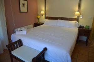 托塔纳桑塔花园旅馆的卧室配有一张白色大床和椅子