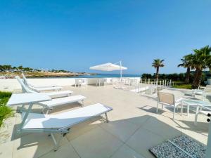 奇尼斯Torre Pozzillo Beach的一个带白色桌椅的庭院和海滩