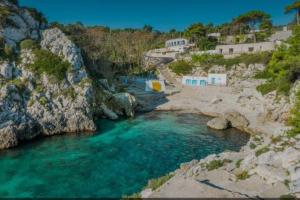 马里蒂玛Salento_Cala Acquaviva a Marina di Marittima (LE)的一条蓝色的河流,岩石和房屋