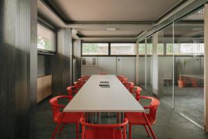 佛罗伦萨'RE-Dama Hostel的一间会议室,配有白色的桌子和红色的椅子