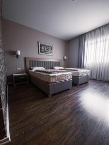 默主歌耶Hotel Laudato的一间卧室设有两张床、一个窗户和木地板。