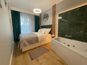 马佐夫舍地区新庄园Caroline Jacuzzi Apartments的一间卧室配有一张床和浴缸