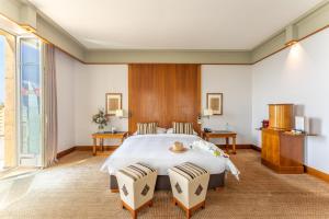 纳沙泰尔美岸酒店的一间卧室配有一张大床和两把椅子