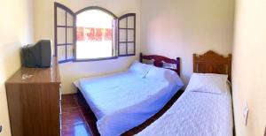 康赛瓦托利亚Recanto da roça的一间卧室设有两张床、一台电视和一扇窗户。