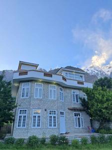 Karimabad HunzaAmn e Yal- Private Family Residence in Hunza的一座大砖砌建筑,背景是群山