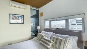 布宜诺斯艾利斯Hollywood Suites & Lofts的卧室配有带枕头的床铺和窗户。
