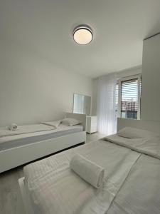 GjakoveGega Apartments的白色卧室配有两张床和一盏灯