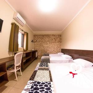 奥林匹亚Pousada Toca das Águas的酒店客房带两张床和砖墙