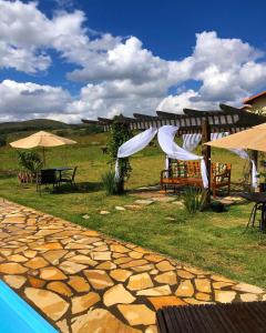 卡兰卡斯Chalés para temporada - Chalés Apuã - 500 metros da Cachoeira的游泳池旁带桌子和遮阳伞的天井