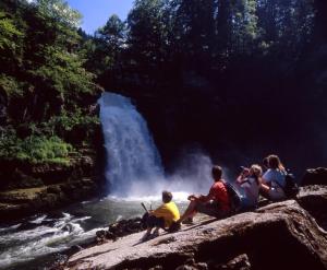 乐罗西三皇酒店的一群人坐在瀑布附近的岩石上