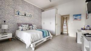 东伦敦Blue's Guest House - East London Bonza Bay的卧室配有白色的床和墙壁