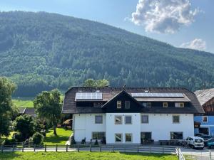 圣迈克尔隆高Landhaus Lungau的一座白色的房子,上面有太阳能电池板,还有一座山