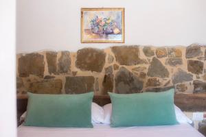 蓬塔谢韦Podere Belvedere Tuscany的一张带两个绿色枕头的床铺,位于石墙前