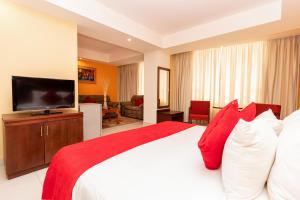 波拉马尔Hotel Faranda Express Puerta del Sol Porlamar的一间卧室配有一张带红色和白色枕头的大床