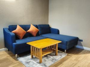 曼谷Baan Nonzee Condo的蓝色的沙发、橙色枕头和木桌