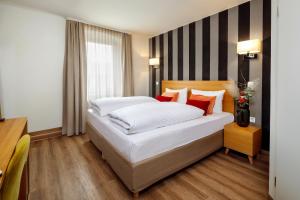 雷根斯堡皮特斯托酒店的一间卧室配有带白色床单和红色枕头的床。
