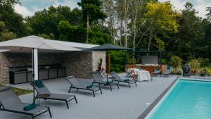 拉特斯特德布赫LA MAISON CACHEE-BA的一个带桌椅和遮阳伞的游泳池、一张桌子和一个游泳池