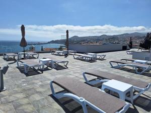 丰沙尔Apartments Madeira Barreirinha的庭院里摆放着桌椅和遮阳伞