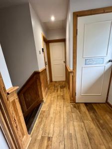 布罗姆利Cosy Single Room for ONE person的空的走廊,有白色的门和木地板